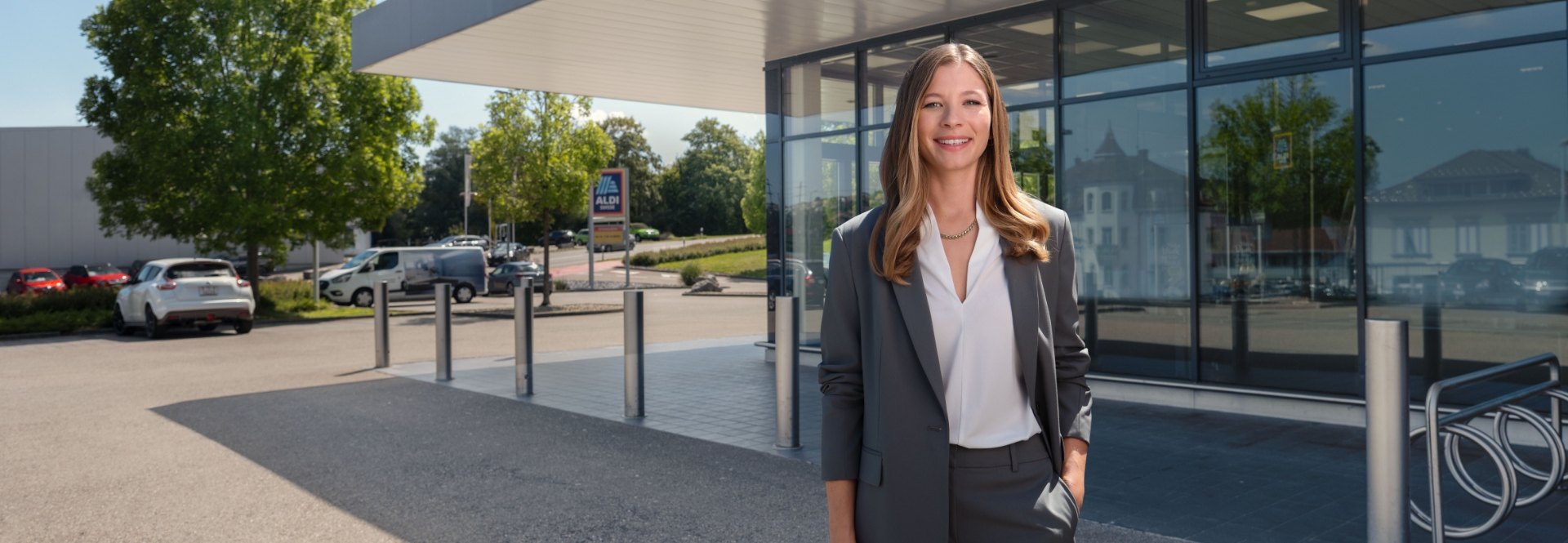 Una donna si trova davanti una filiale ALDI Suisse e sorride.