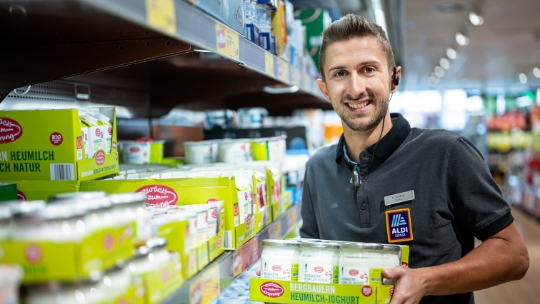 Un homme range des yogourts dans les rayons d'une filiale ALDI Suisse.