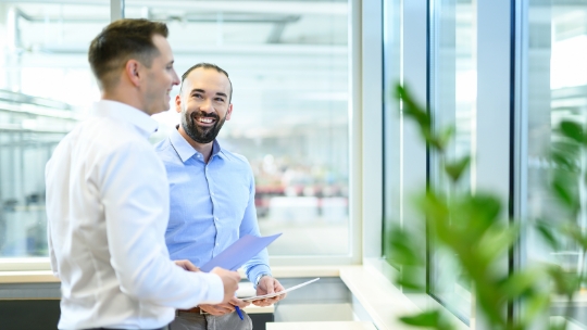 Deux hommes discutent de documents qu'ils ont entre les mains.