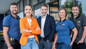 Un groupe de collaborateurs d'ALDI Suisse se tiennent ensemble devant une filiale d'achat d'ALDI Suisse.