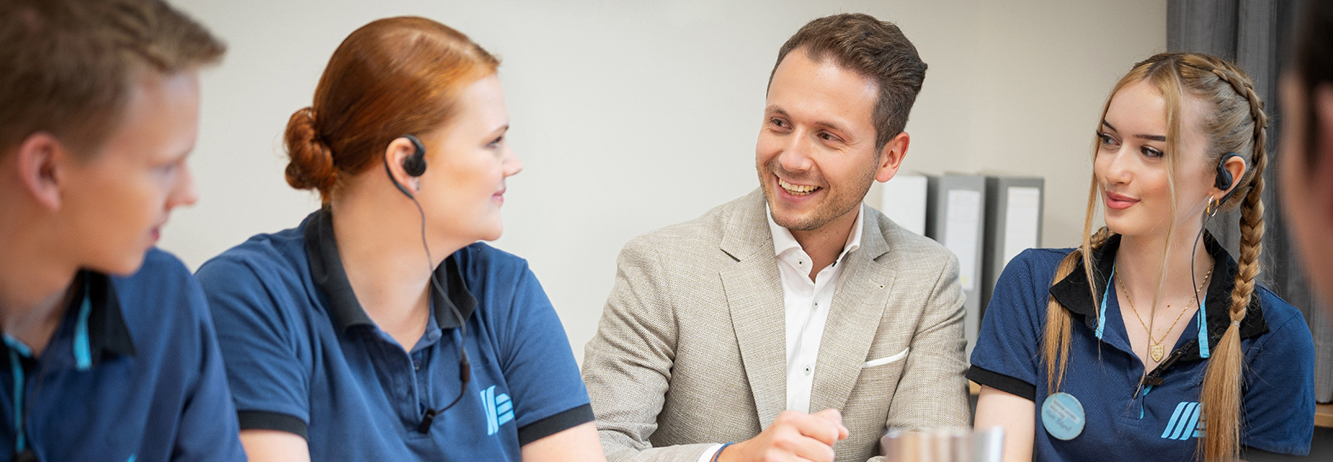 Vier ALDI Suisse Mitarbeiter sitzen in der Mittagspause an einem Tisch und besprechen etwas.