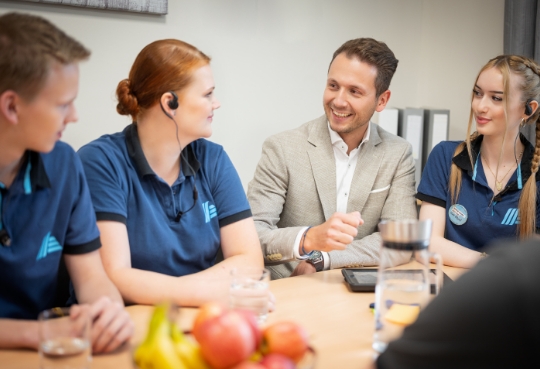 Quatre collaborateurs d'ALDI Suisse sont assis à une table pendant la pause de midi et discutent de quelque chose.