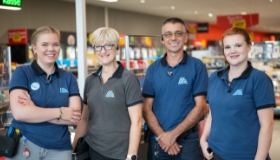 Un groupe de collaborateurs d'ALDI Suisse se tiennent ensemble devant une caisse.